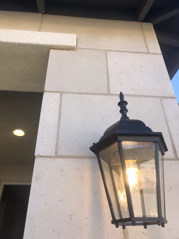 Limestone veneer trims the entry wall beside a black lantern light fixture.