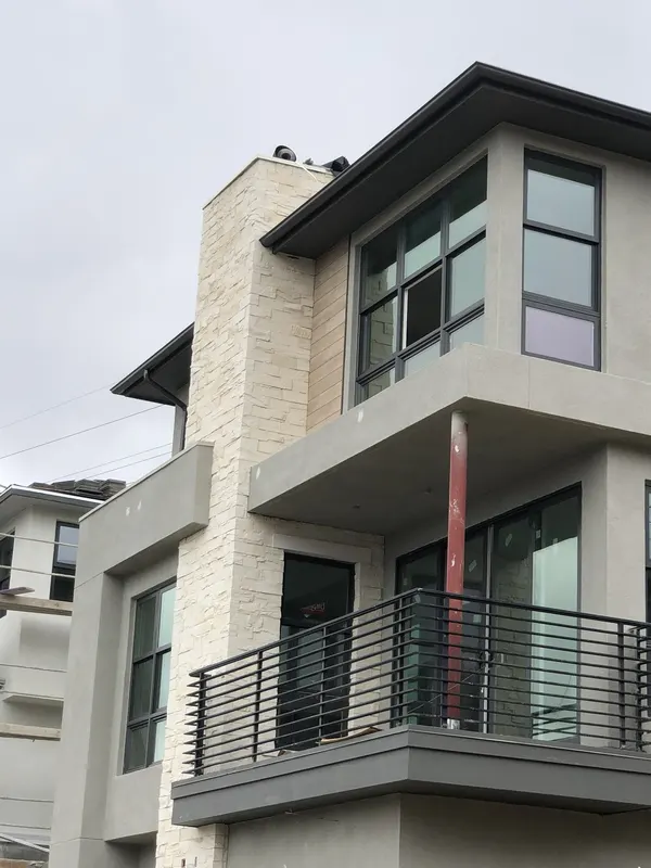 Pale stacked stone veneer forms a full-height chimney and corner accent on this modern home.